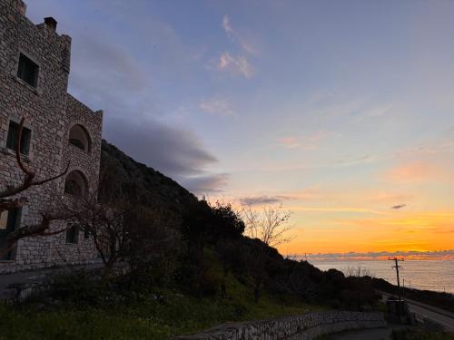 a building on a hill with the sunset in the background at Vatoulia House in Neon Oitilon