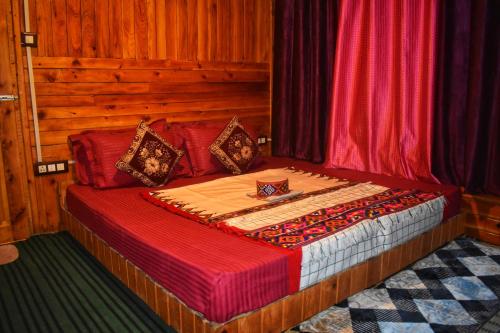 a bed in a room with wooden walls and curtains at Rustic wood house - A village home stay in Jibhi Valley in Jibhi