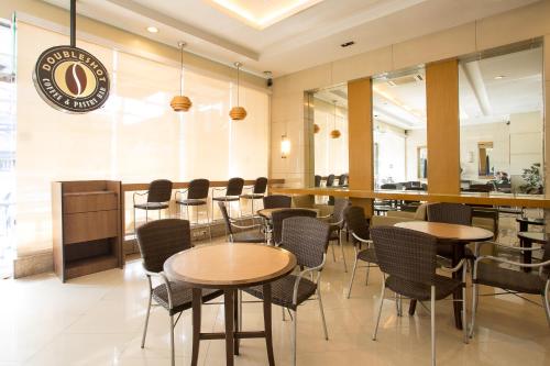 un restaurante con mesas y sillas y un bar en Vieve Hotel, en Manila