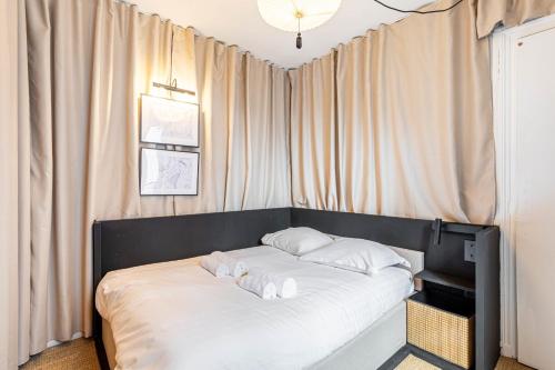 un lit avec des draps blancs et des oreillers dans une chambre dans l'établissement Flexliving - T2 - Crozatier, à Paris