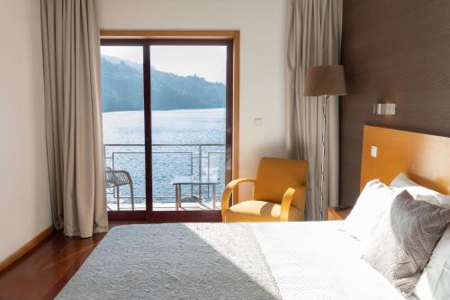 a bedroom with a bed and a view of the water at Douro Hotel Porto Antigo in Cinfães