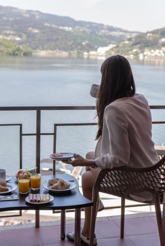 a woman sitting at a table with plates of food at Douro Hotel Porto Antigo in Cinfães