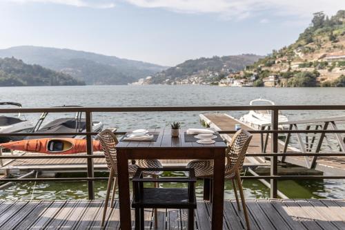a table and chairs on a dock next to a boat at Douro Hotel Porto Antigo in Cinfães
