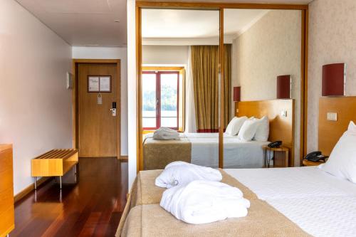 a hotel room with two beds and a mirror at Douro Hotel Porto Antigo in Cinfães