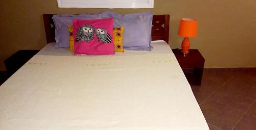 ein Bett mit zwei Eulenkissen drauf in der Unterkunft Kalahari Estate, Prestige & Quiet in Sali Poulang