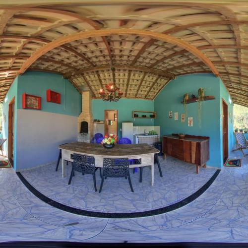 a living room with a table and a kitchen at Pousada Sítio da Floresta in Sana