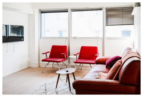 a living room with two red chairs and a couch at Beau 3P à 20m du métro et 20 min du cœur de Paris in Les Lilas