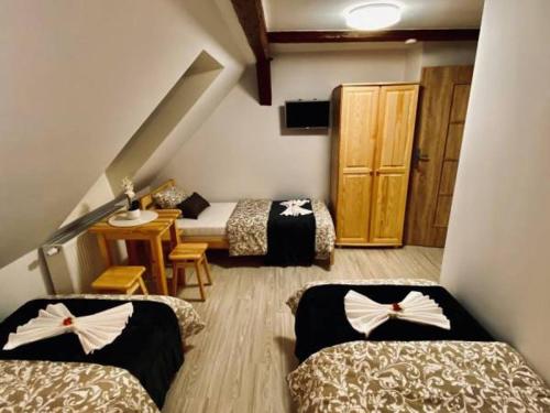 a room with three beds and a table and a staircase at Noclegi Pocztowa 1 in Lubawka