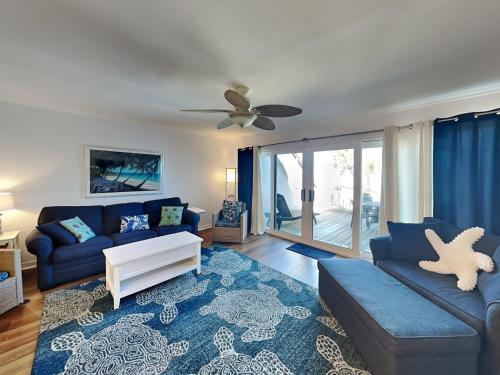 a living room with a blue couch and a ceiling fan at Sea Matanzas 2 in Saint Augustine