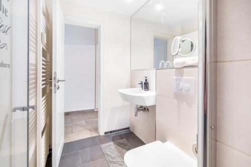 a white bathroom with a sink and a toilet at Urban Retreat Apartment - Whirpool - Top Lage in Cologne