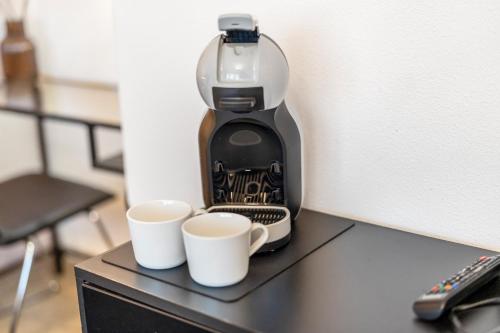 a coffee maker sitting on top of a table with two cups at Urban Retreat Apartment - Whirpool - Top Lage in Cologne