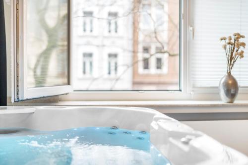 a bath tub filled with blue water next to a window at Urban Retreat Apartment - Whirpool - Top Lage in Cologne
