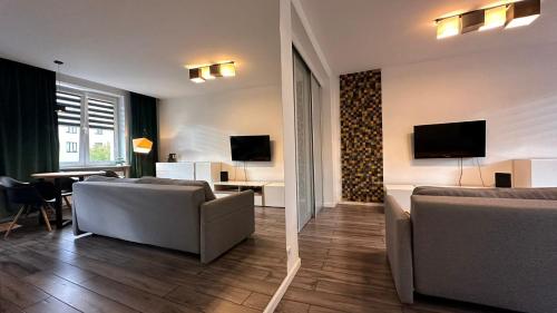 a living room with two couches and a living room with a table at Apartament Skandynawski Sienkiewicza 13 in Kielce
