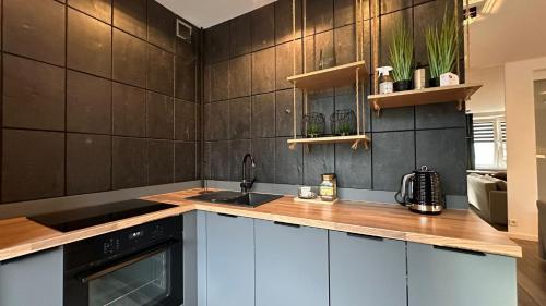 a kitchen with a black tiled wall at Apartament Skandynawski Sienkiewicza 13 in Kielce