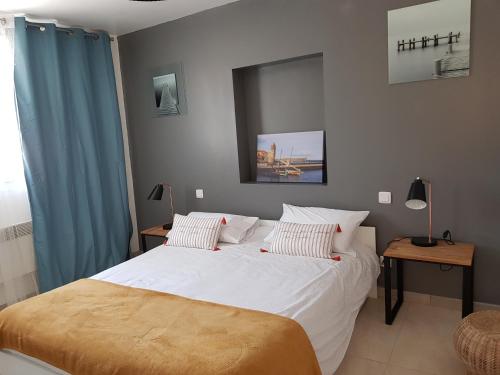 - une chambre avec un grand lit blanc et des rideaux bleus dans l'établissement la Cigale, à Collioure