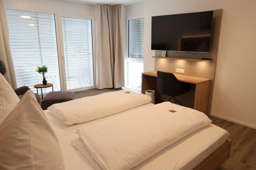 a hotel room with two beds and a desk and a television at MEIN MOTEL - Self Check-in in Oberndorf am Neckar