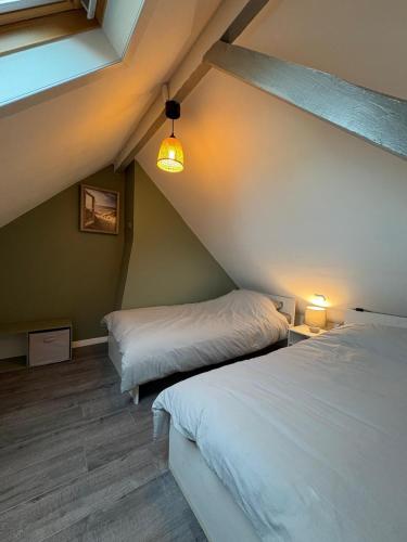 Cette chambre mansardée comprend deux lits et une lampe. dans l'établissement Apartemment Place Delta Malo Plage, à Dunkerque