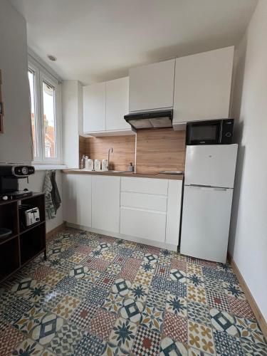 une cuisine avec des armoires blanches et un sol carrelé dans l'établissement Apartemment Place Delta Malo Plage, à Dunkerque