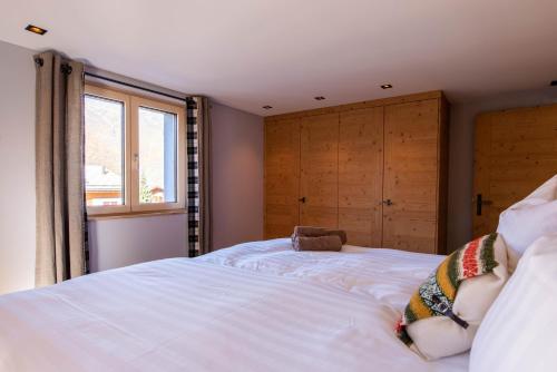 a bedroom with a large white bed with a window at Chalet Myriam in Grächen