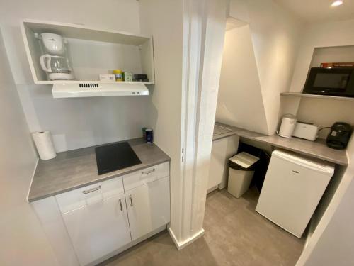 une petite cuisine avec des armoires blanches et un micro-ondes dans l'établissement Séjour au cœur du centre, proche de la République - 138, à Rouen