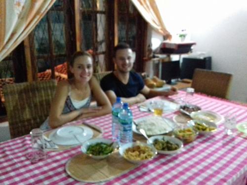 a man and woman sitting at a table with food at The villa sunshine kadawala in Dunagaha
