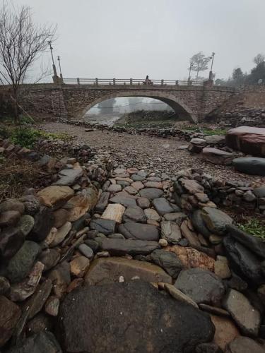 a bridge over a river with rocks and a bridge at Little House in KhauPha, Mu Cang Chai - homestay, cuisine, cafe in Mù Cang Chải