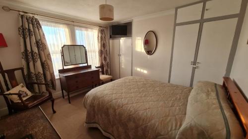 a bedroom with a bed and a dresser and a mirror at Avon Manor Guest House in Lee-on-the-Solent