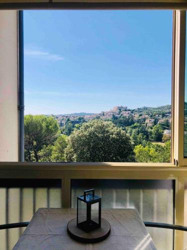 Cette chambre dispose d'une grande fenêtre avec une table et une vue. dans l'établissement Grand Studio proche cure&village, à Gréoux-les-Bains