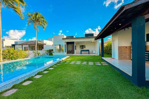 un cortile con piscina e una casa di Casa Brilho Do Mar a Camaçari