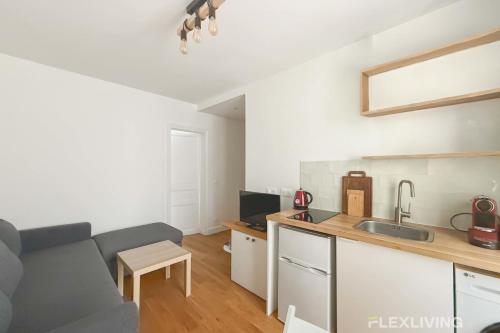 un salon avec un canapé et une cuisine dans l'établissement Boucry - Charming and Bright One-Bedroom Apartment in the Heart of the 18th, à Paris