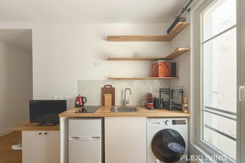 une cuisine avec une machine à laver et un évier dans l'établissement Boucry - Charming and Bright One-Bedroom Apartment in the Heart of the 18th, à Paris