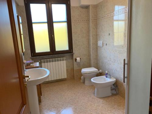 a bathroom with a sink and a toilet and a window at Casa del Melograno Outlet in Serravalle Scrivia