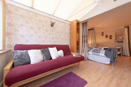 a living room with a red couch and a bed at 3bedroom Sleeps8 Parking FamilyFriendly NearExcel in London