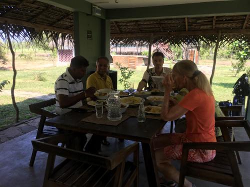 a group of people sitting around a wooden table at Lake10 Eluwankulama in Mulakandaveli