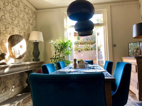 a dining room with a table and blue chairs at Saskia's Rooms in Winchester