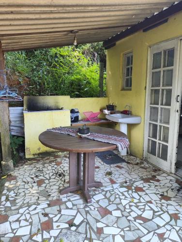 a patio with a wooden table on a stone patio at Pousada Pitoresca Casa Amarela in Mairiporã