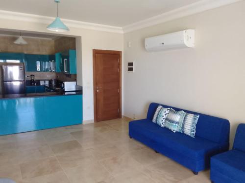 a living room with a blue couch and a kitchen at La Vista Luxorious Chalet North Coast Egypt in Ras Elhekma