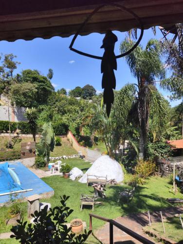 a statue of a woman hanging from a tree next to a pool at Pousada Pitoresca Casa Amarela in Mairiporã