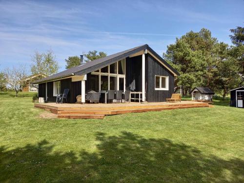 a black house with a large deck in a field at Sommerhus Ved Hvalpsund in Farsø