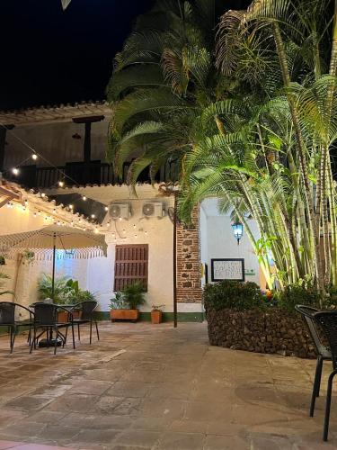 a patio with tables and chairs and palm trees at Casa hotel Dulce Candelaria in Santa Fe de Antioquia