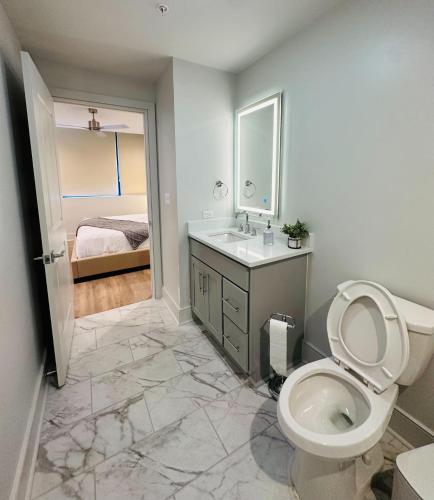a bathroom with a toilet and a sink and a bed at The Eleanor New Orleans in New Orleans