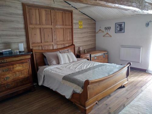- une chambre avec un lit en bois et une commode en bois dans l'établissement Maison de famille, à Saint-Jean-de-Sauves