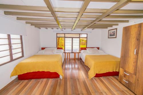 two beds in a room with white walls and wooden floors at Finca Formentera, este tu pequeño paraíso in Dosquebradas
