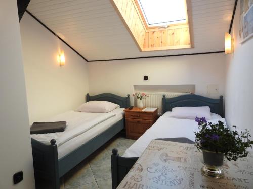 two beds in a room with a table and a skylight at Elizabeth Łeba - Pokoje Gościnne in Łeba