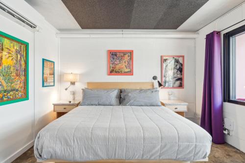 a bedroom with a large bed with purple curtains at Boutique Vera Hotel in the Heart of Folly Beach in Folly Beach