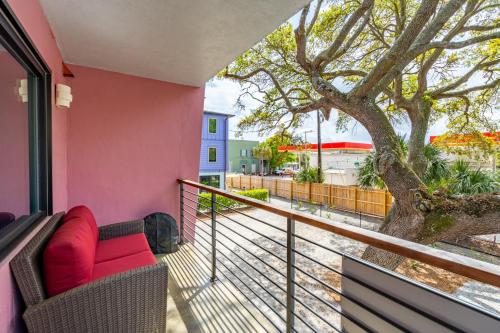 a balcony with a red couch and a tree at Boutique Vera Hotel in the Heart of Folly Beach in Folly Beach