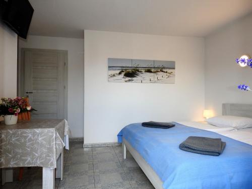 a bedroom with a bed and a table and a picture at Elizabeth Łeba - Pokoje Gościnne in Łeba