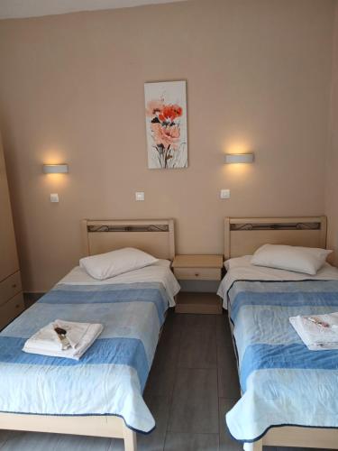 two beds in a hotel room with towels on them at Vassilis Studios in Anaxos