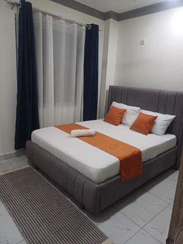 a bed with orange and white pillows in a room at Es Su Casa in Mombasa