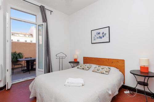 une chambre blanche avec un lit et un balcon dans l'établissement Bessons, à Cannes